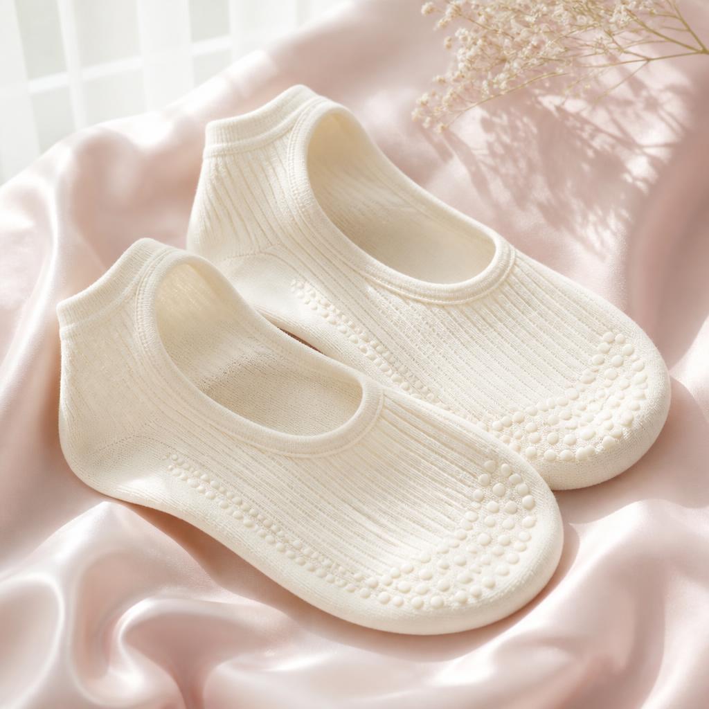 Pair of ivory cream ribbed grip socks on pale pink silk