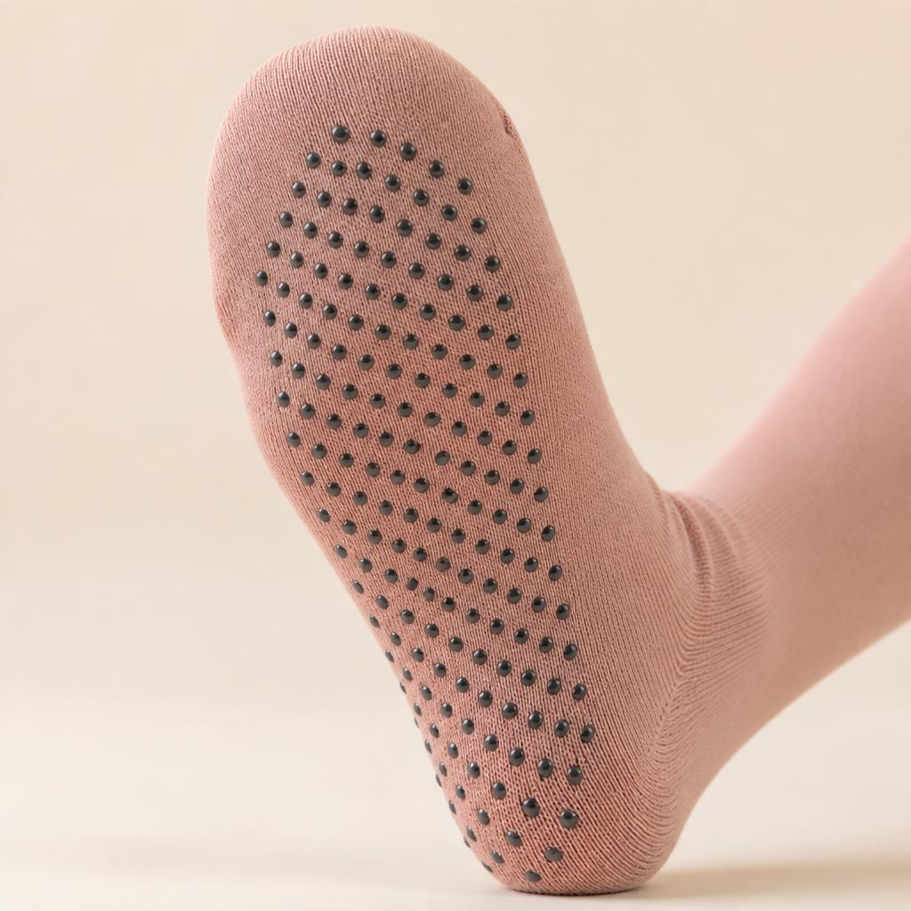 Close-up of dusty rose grip sock sole with black grip dots